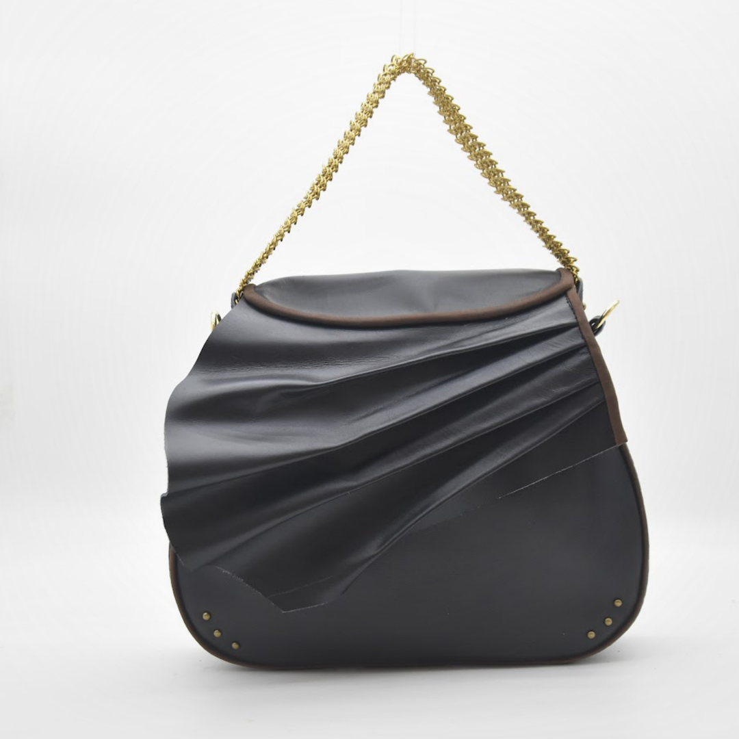 ISIS saddle bag in draped, sculpted black leather with a brass chain in gold, front view, Patricia Bos Designs