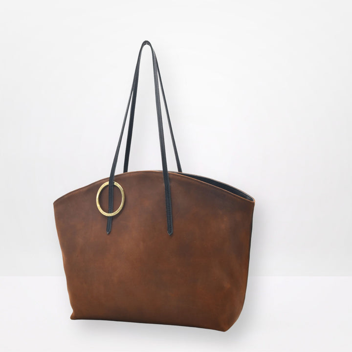 Brown leather tote bag with black straps on a white background