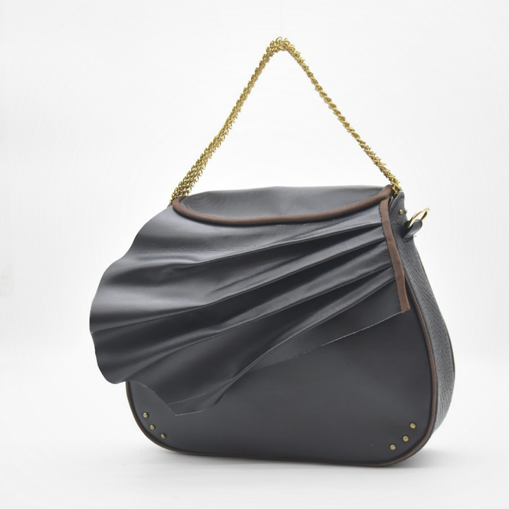 ISIS black leather saddle bag carried as a handbag, sculpted leather wave