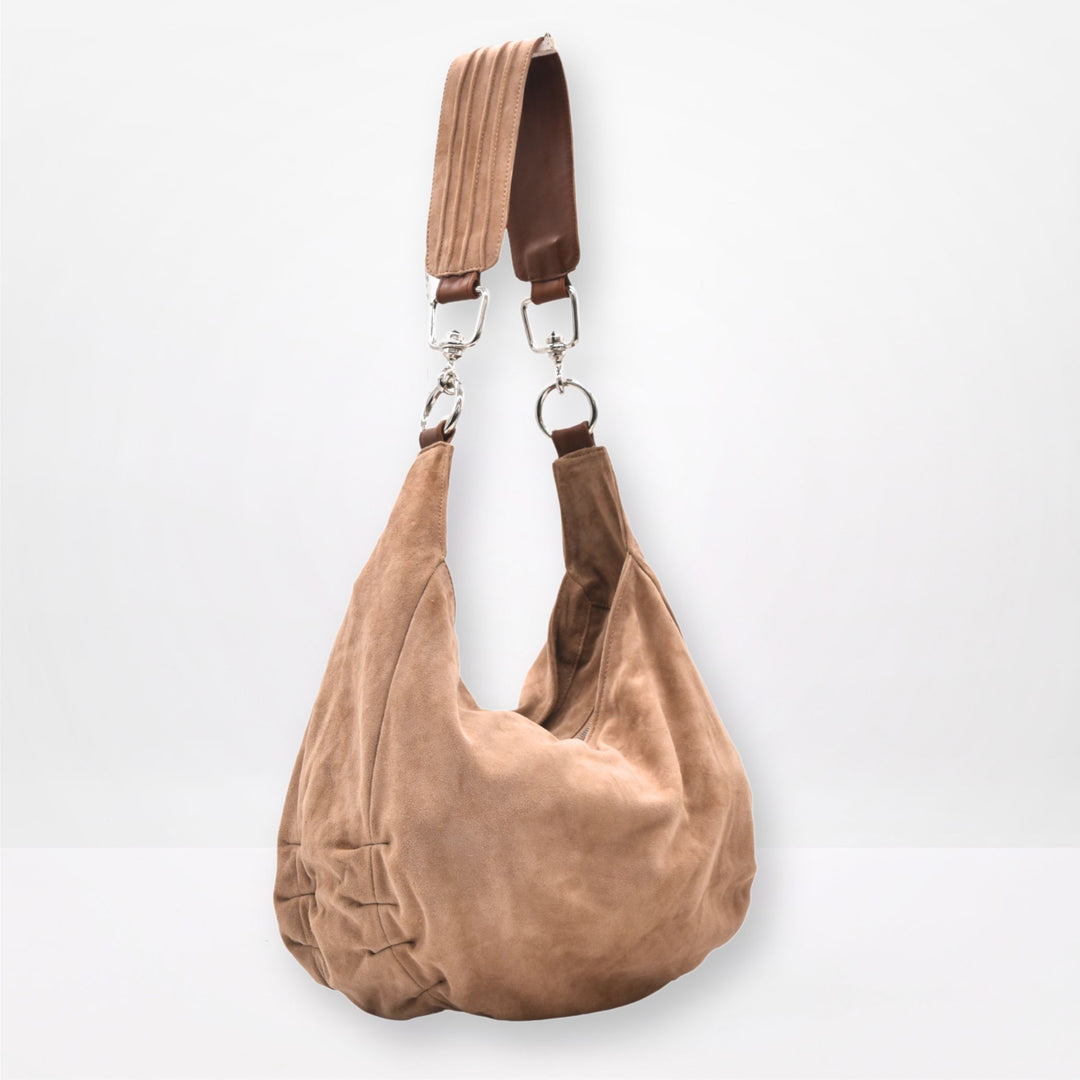 sand tan  suede handbag with a strap on a light gray background
